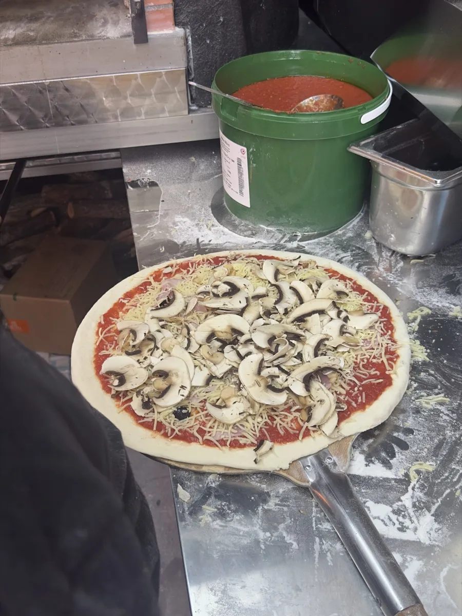 Une pizza cuite et gratinée sort du four à bois, Pizza Thaololo Pierrevert